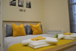 a bed with yellow pillows and towels on it at OnPoint - 2 Bed Apartment City Centre Ideal Location! in Nottingham