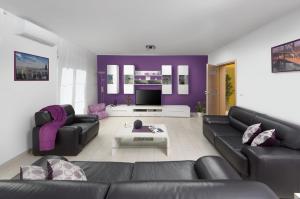 a living room with two black couches and a purple wall at RAINBOW in Pula