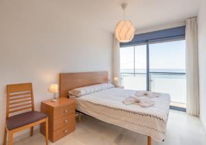 a bedroom with a bed and a chair and a window at Apartamentos Varadero Sea View in Cala del Moral