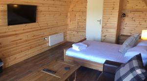 Habitación con cama, TV y sofá. en Superior Glamping Pod with Hot Tub en Frodsham