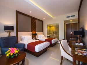 um quarto de hotel com duas camas e uma cadeira e uma secretária em Puri Asri Hotel & Resort em Magelang