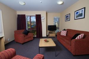 un soggiorno con 2 divani rossi e una TV di Alhambra Oaks Motor Lodge a Dunedin