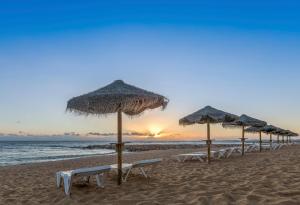 a row of umbrellas and chairs on a beach at Dom Jose Beach Hotel (Plus) in Quarteira