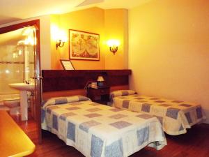 a hotel room with two beds and a bathroom at Hotel Castilla in Antequera