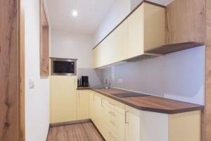 a kitchen with white cabinets and a sink and a microwave at Hotel Appartement Inge in Tirolo