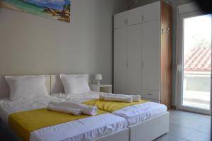 a bedroom with two beds with white sheets and a yellow blanket at Daisy Apartment in Asprovalta