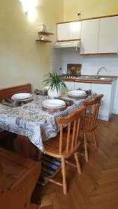 uma cozinha com uma mesa com quatro cadeiras e uma mesa em APPARTAMENTO FRANCESCO GIUSEPPE em Colle Isarco