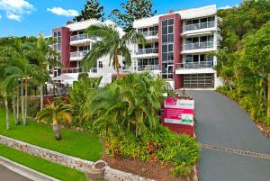 an apartment complex with palm trees and a driveway at Bali Hai Apartments Noosa in Noosa Heads
