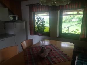 eine Küche mit einem Holztisch und 2 Fenstern in der Unterkunft Apartma PR PEKOVCU in Bohinj