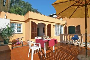 eine Terrasse mit einem Tisch, Stühlen und einem Sonnenschirm in der Unterkunft Appartamenti Villa Chiara in Imperia