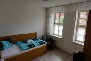 Un dormitorio pequeño con una cama y dos ventanas. en Ferienwohnung Ballstrasse 28, en Quedlinburg