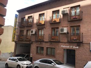 two cars parked in front of a brick building at El Sueño del Infante in Guadalajara