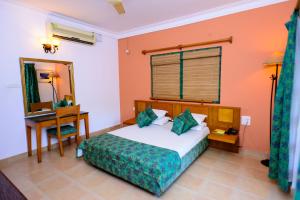 a bedroom with a bed and a desk and a table at Bellflower Alidia Beach Resort in Baga