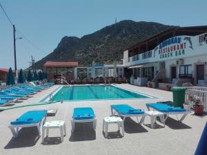 a swimming pool with blue and white chairs and a hotel at Andreas Apartments in Kefalos