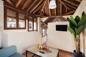 sala de estar con mesa y TV en Urban Suites Granada, en Granada