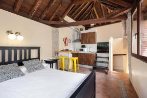 ein Schlafzimmer mit einem Bett und eine Küche mit gelben Stühlen in der Unterkunft Urban Suites Granada in Granada