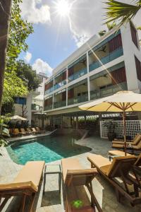 a pool with chairs and umbrellas in front of a building at Rambutan Resort – Phnom Penh in Phnom Penh