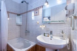 a white bathroom with a sink and a tub at Mirabeli Apartments & Suites in Pollonia