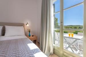 a bedroom with a bed and a balcony with a table at Mirabeli Apartments & Suites in Pollonia