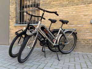 Dos bicicletas están estacionadas junto a una pared de ladrillo. en Alibi Hostel Leeuwarden, en Leeuwarden