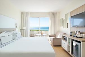 een witte hotelkamer met een groot bed en een televisie bij Melia Sitges in Sitges