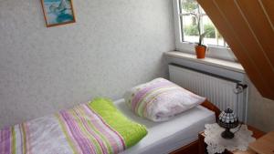 a bedroom with a bed with a pillow and a window at Ruhige Unterkunft nahe der Nordsee in Friedeburg