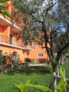 un edificio arancione con un albero di fronte di Albergo Villa Mimosa a Torbole