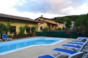 a swimming pool with chairs and a house at Agriturismo Mandrola in Rivergaro