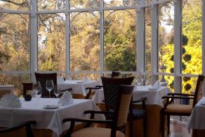un restaurante con mesas y sillas blancas y ventanas grandes en Château Visz, en Visz