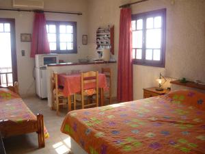 a bedroom with two beds and a kitchen with a table at Villa Victoria in Makry Gialos