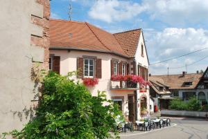 een gebouw met een balkon met tafels en stoelen bij Hôtel Restaurant Kleiber in Saint-Jean-Saverne