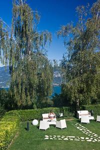 a woman sitting on a bench in the grass at Hotel Costabella in San Zeno di Montagna