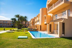 a building with a swimming pool in front of a building at AQI Skanes Resort in Monastir
