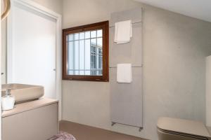 a bathroom with a sink and a toilet and a window at Pgrhome Luxury Apartments Coral Loft Venice in Venice