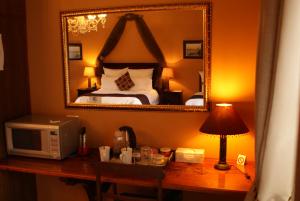 een hotelkamer met een bed en een bureau met een magnetron bij Hampton House Guest House in Centurion
