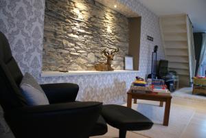 sala de estar con silla y pared de piedra en Le gîte de l Ourthe, en Ortheuville
