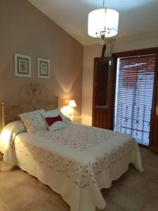 1 dormitorio con cama blanca y ventana en Apartamentos Rurales Tía María en Mata de Alcántara
