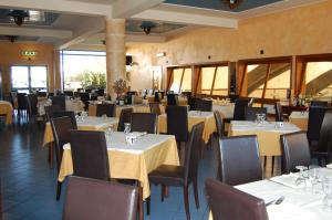 Marina di MelilliにあるHotel Club Pegasoのダイニングルーム(白いテーブル、椅子付)