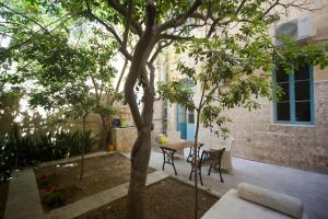 a patio with a table and chairs under a tree at The Maltese Sun in Sliema