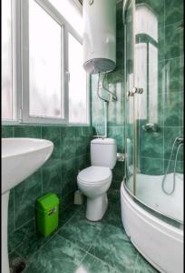 a green bathroom with a toilet and a sink at Enjoy The Hostel in Batumi