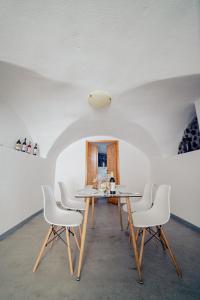 a dining room with a table and white chairs at Pueblo Viejo Suites in Kamari