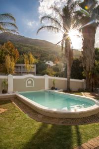 a swimming pool in a yard with a palm tree at Pontac Manor Hotel & Restaurant in Paarl