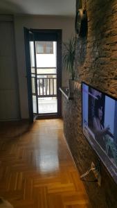 een woonkamer met een flatscreen-tv aan een stenen muur bij Zlatibor Apartman Pantic in Zlatibor