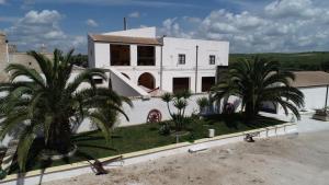 a white house with palm trees in front of it at Agriturismo Masseria Santa Lucia al Bradano in Matera