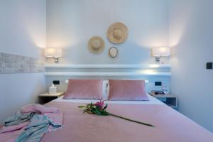 een bed met roze kussens en een bloem erop bij Sonio Beach - Que Bella Collection in Plataniás