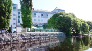 um edifício junto a um rio em frente a um edifício em Original Sokos Hotel Vaakuna Hämeenlinna em Hämeenlinna