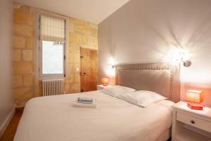 um quarto com uma grande cama branca e 2 candeeiros em Appart Hypercentre - Le Dijeaux em Bordeaux