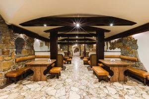 a restaurant with wooden tables and benches and a stone wall at Ośrodek Wypoczynkowy Tarnica in Solina