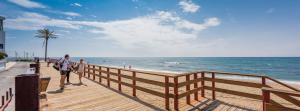 a man and a woman standing on a boardwalk at the beach at Macdonald Leila Playa Resort in La Cala de Mijas