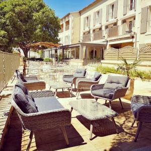 una fila de sillas y mesas de mimbre en un patio en Hôtel Belesso, en Fontvieille